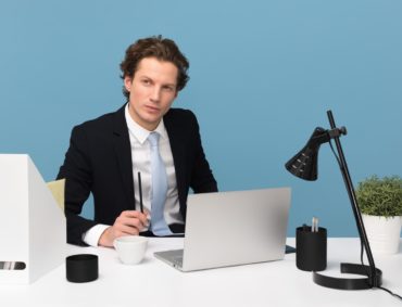 Man Sitting WIth Laptop computer on desk with lamp